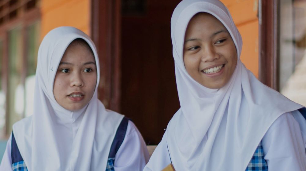 Two Indonesian school girls wearing hijab smile 