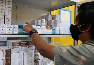 A person reaches antiretroviral medicines from a shelf.