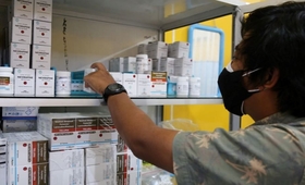 A person reaches antiretroviral medicines from a shelf.