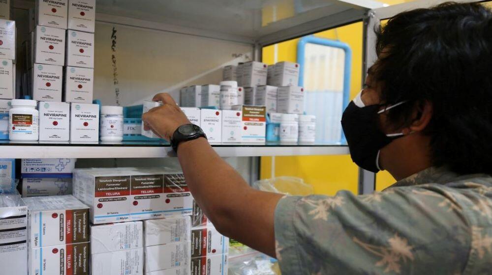 A person reaches antiretroviral medicines from a shelf.